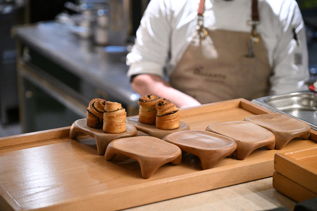 Chef presenting pastries on a wooden tray during a live event
